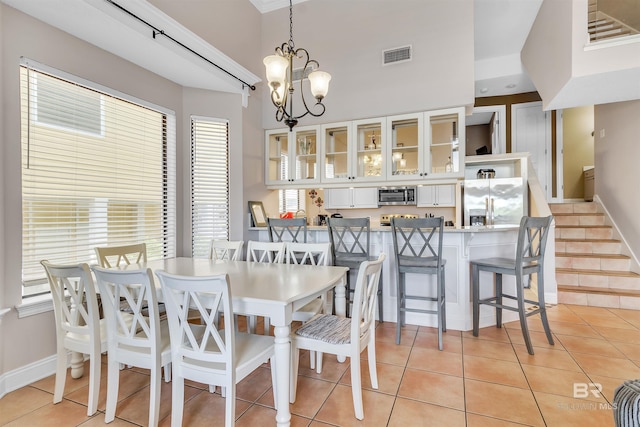 201 W 13th St Unit 2 B, Gulf Shores, AL 36542 - dining space featuring light tile patterned floors, a chandelier, baseboards, and stairway