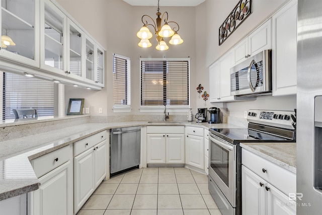 201 W 13th St Unit 2 B, Gulf Shores, AL 36542 - kitchen featuring stainless steel appliances, a sink, a chandelier, light tile patterned flooring, and a towering ceiling