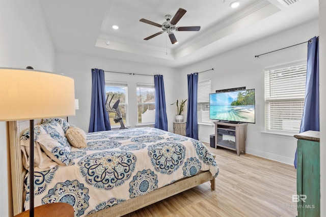 bedroom featuring baseboards, a raised ceiling, ceiling fan, wood finished floors, and crown molding