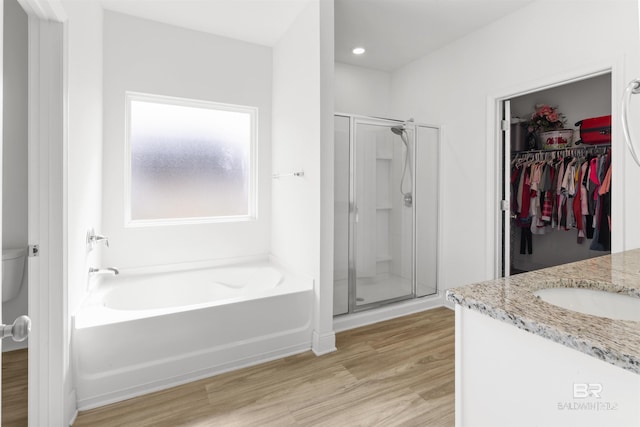 bathroom featuring a garden tub, wood finished floors, vanity, and a shower stall