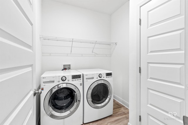 washroom featuring laundry area, independent washer and dryer, light wood-style flooring, and baseboards