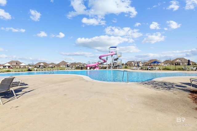 community pool featuring a patio and a water slide