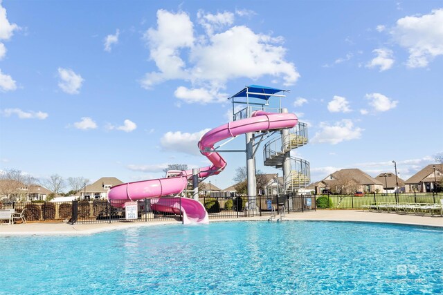 view of pool featuring a water slide and fence