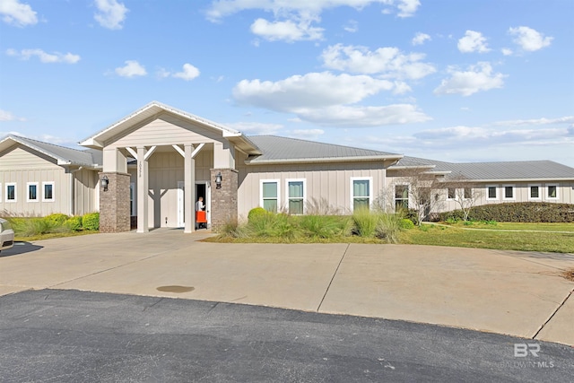 view of front of property with board and batten siding, metal roof, driveway, and an attached garage