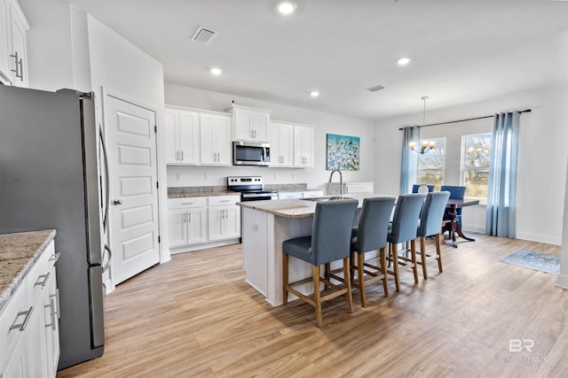 kitchen featuring appliances with stainless steel finishes, light wood-type flooring, visible vents, and white cabinetry