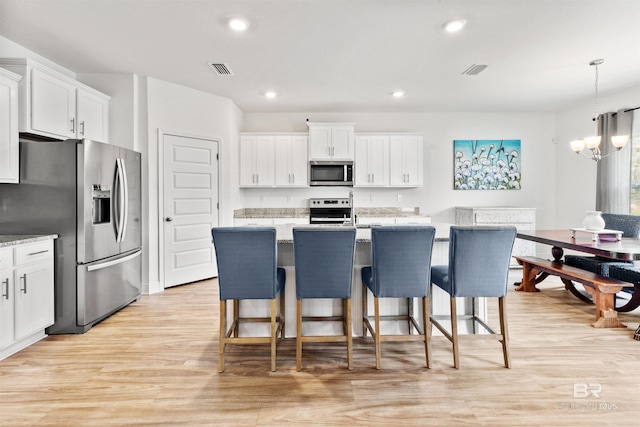 kitchen featuring stainless steel appliances, visible vents, light wood-style floors, white cabinets, and an inviting chandelier