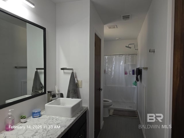 bathroom featuring hardwood / wood-style flooring, vanity, toilet, and walk in shower