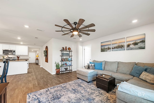 living area with wood finished floors, recessed lighting, baseboards, and ceiling fan