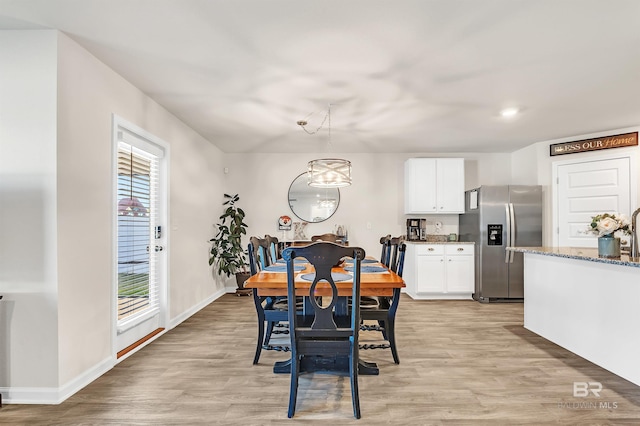 dining space with light wood finished floors, baseboards, and a chandelier