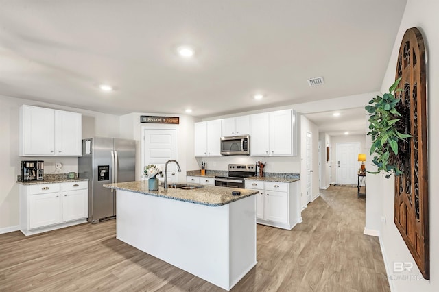 kitchen with appliances with stainless steel finishes, a sink, light wood-type flooring, light stone countertops, and recessed lighting