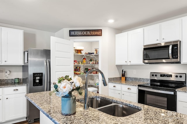 kitchen with stainless steel appliances, a sink, white cabinetry, light stone counters, and recessed lighting