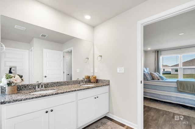 ensuite bathroom with wood finished floors, baseboards, double vanity, and recessed lighting