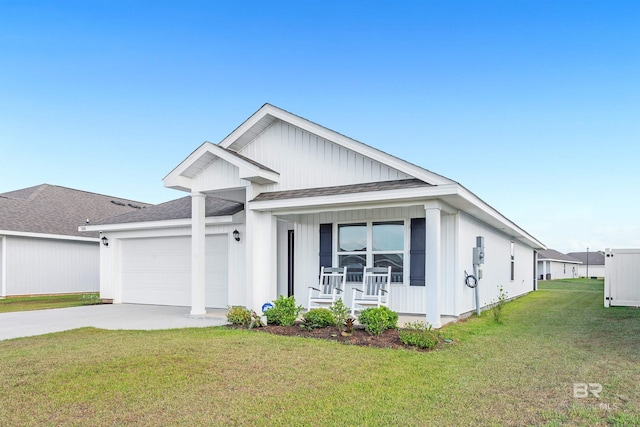 view of front facade with a porch, a front yard, an attached garage, concrete driveway, and roof with shingles