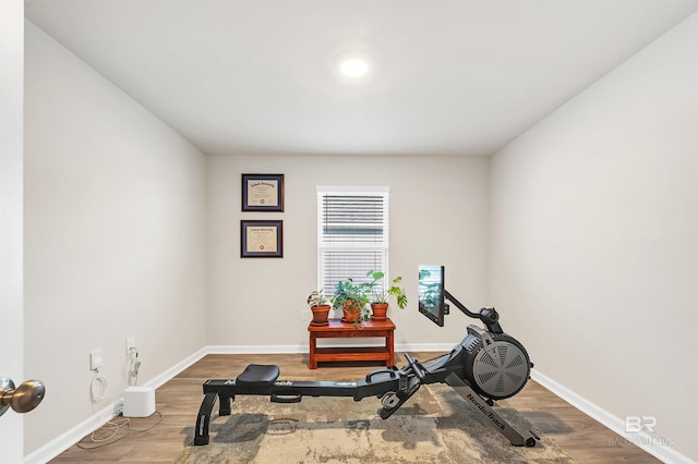 exercise room with baseboards and wood finished floors