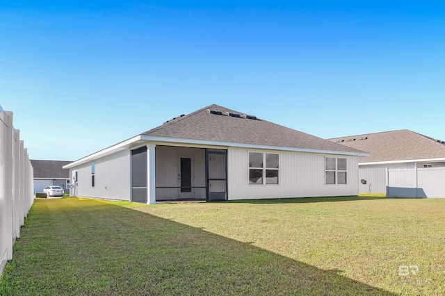 rear view of property featuring roof with shingles, a yard, and a sunroom