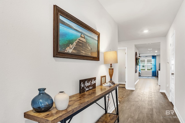 hallway with wood finished floors, baseboards, and recessed lighting