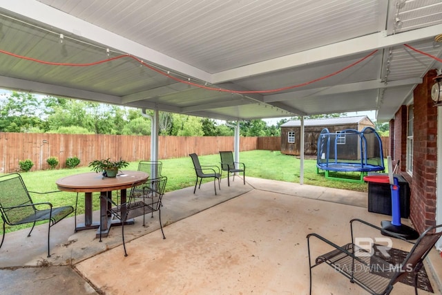 10234 Scott Plantation Dr, Mobile, AL 36695 - fenced backyard featuring a trampoline, a patio area, a storage shed, and outdoor dining area