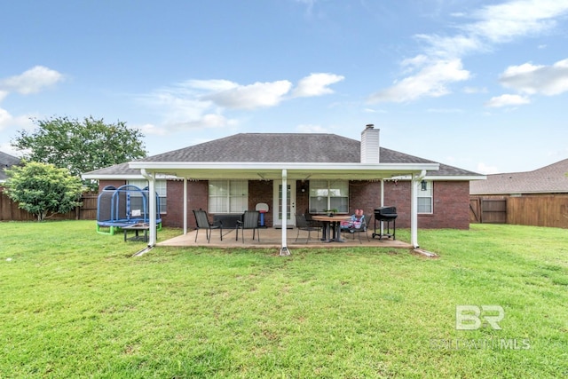 10234 Scott Plantation Dr, Mobile, AL 36695 - rear view of property featuring a trampoline, brick siding, a patio, a fenced backyard, and a chimney