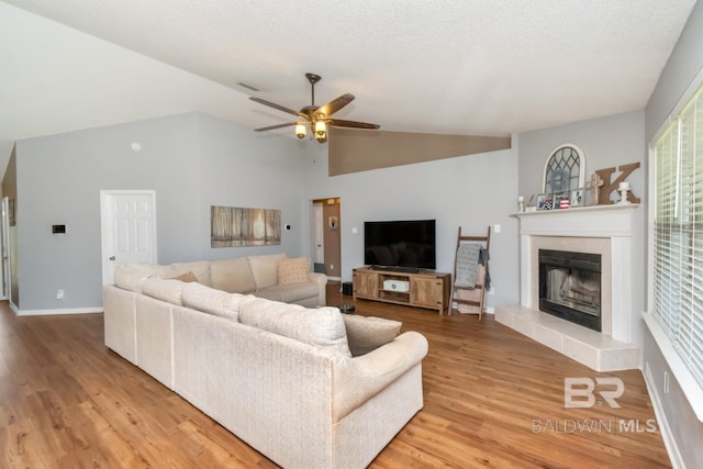 10234 Scott Plantation Dr, Mobile, AL 36695 - living area featuring a ceiling fan, a tiled fireplace, light wood-style flooring, and high vaulted ceiling