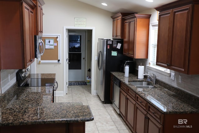 kitchen with dark stone counters, light tile patterned flooring, a sink, decorative backsplash, and appliances with stainless steel finishes