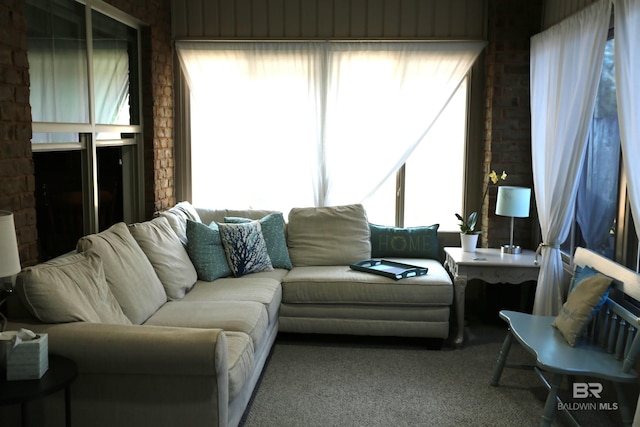 carpeted living room featuring brick wall