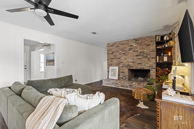 living area featuring a brick fireplace, a ceiling fan, visible vents, and dark wood-type flooring