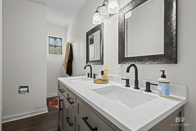 bathroom featuring double vanity, wood finished floors, a sink, and baseboards