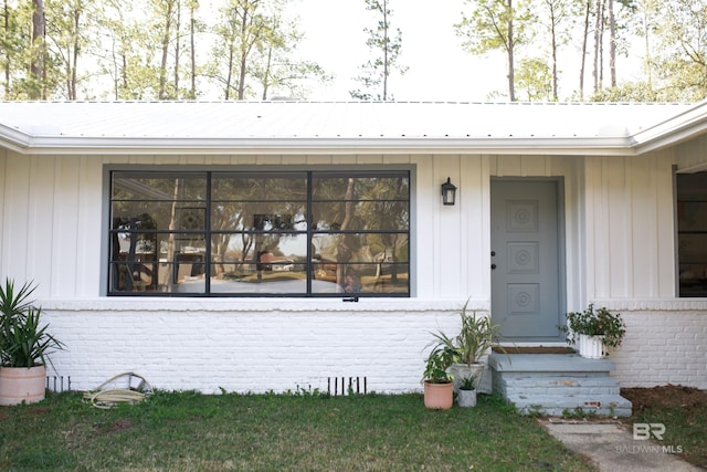 doorway to property with crawl space, brick siding, and metal roof