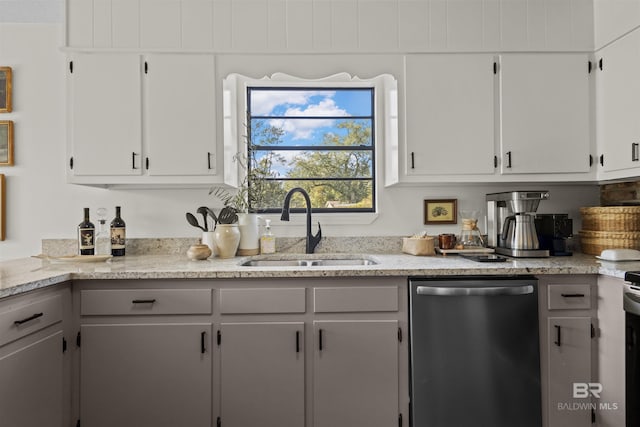 kitchen with a sink, light stone countertops, white cabinets, and stainless steel dishwasher