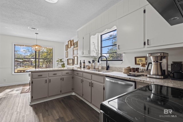 kitchen featuring dark wood finished floors, dishwasher, black electric range oven, a peninsula, and a sink