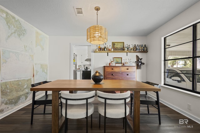 dining room featuring a textured ceiling, dark wood finished floors, visible vents, and baseboards