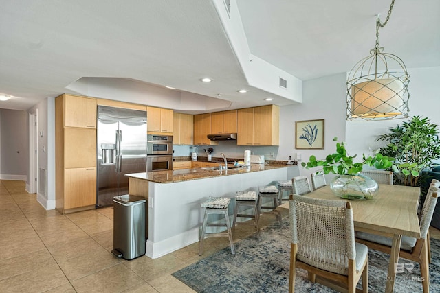 kitchen featuring decorative light fixtures, sink, light tile patterned floors, kitchen peninsula, and stainless steel appliances