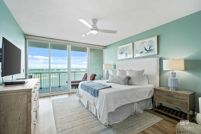 bedroom featuring access to outside, floor to ceiling windows, ceiling fan, and light wood-type flooring