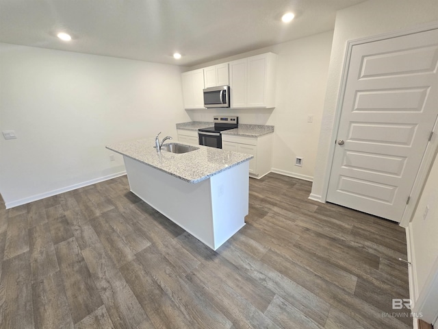 kitchen with electric range, white cabinets, stainless steel microwave, a kitchen island with sink, and a sink