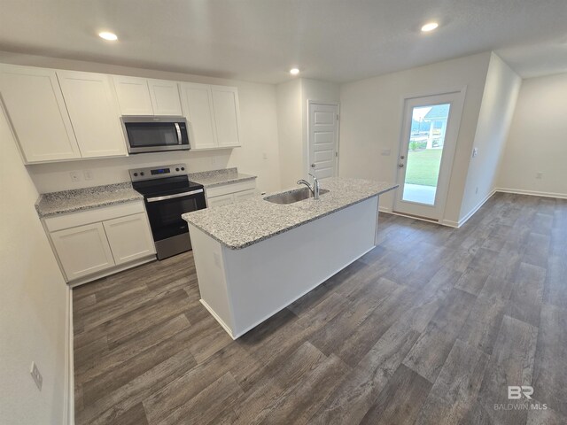 kitchen featuring a kitchen island with sink, stainless steel appliances, dark wood-type flooring, a sink, and white cabinets