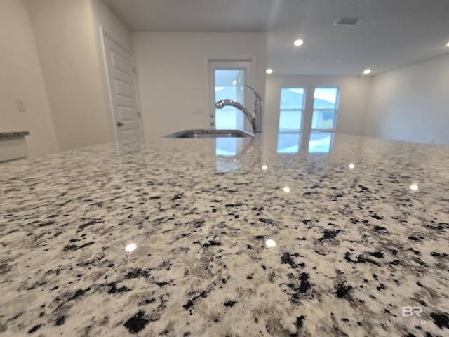 kitchen with a sink, visible vents, and light stone countertops