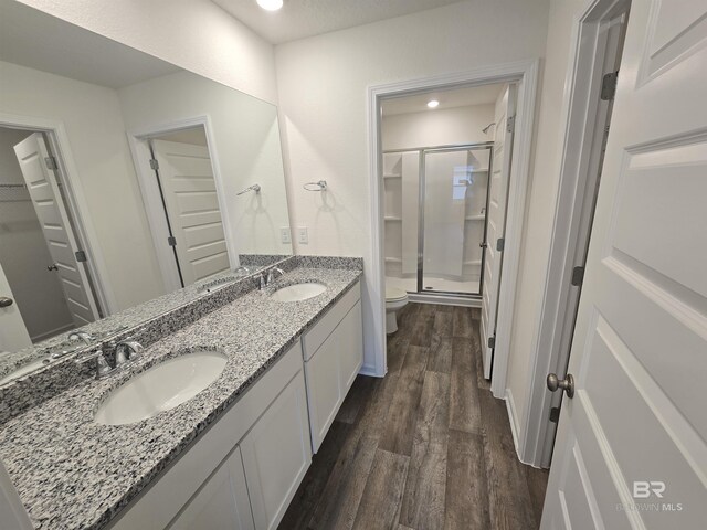 full bath with wood finished floors, a stall shower, a sink, and toilet