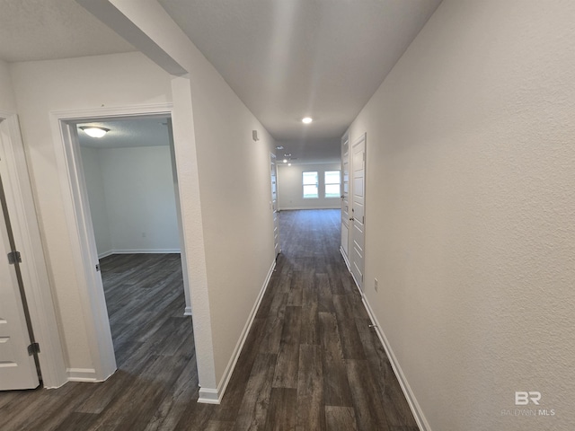 hallway featuring dark wood-style floors and baseboards