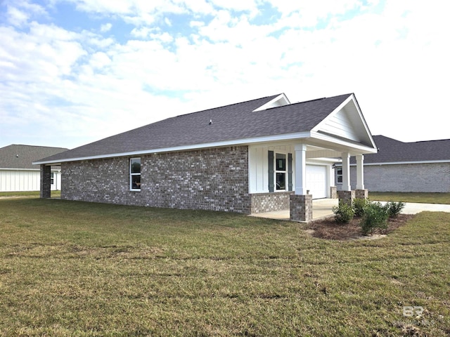 view of side of property featuring a garage, a yard, brick siding, and roof with shingles