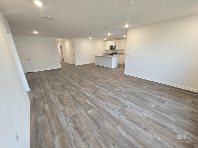 unfurnished living room with light wood-type flooring, visible vents, baseboards, and recessed lighting