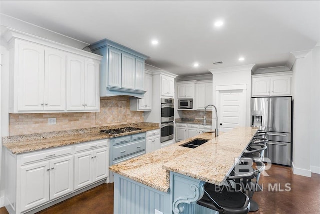 kitchen featuring a kitchen island with sink, a kitchen breakfast bar, sink, appliances with stainless steel finishes, and white cabinetry