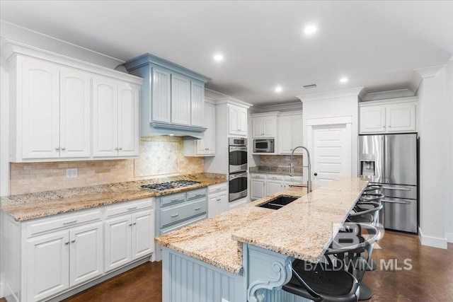 kitchen with a kitchen breakfast bar, sink, an island with sink, appliances with stainless steel finishes, and white cabinetry