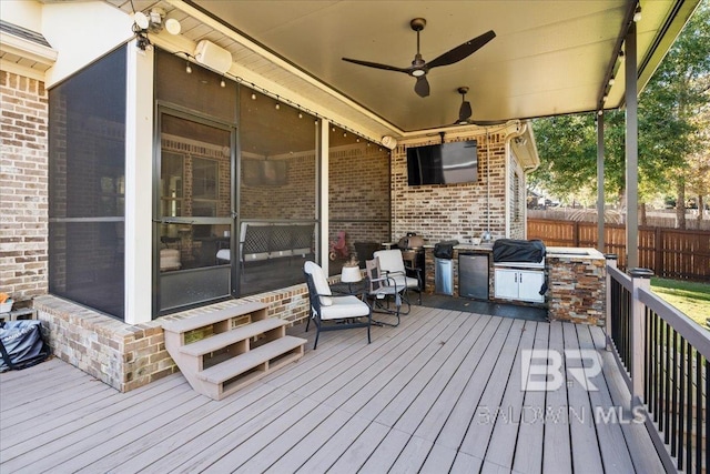 deck with a sunroom, an outdoor kitchen, ceiling fan, and grilling area