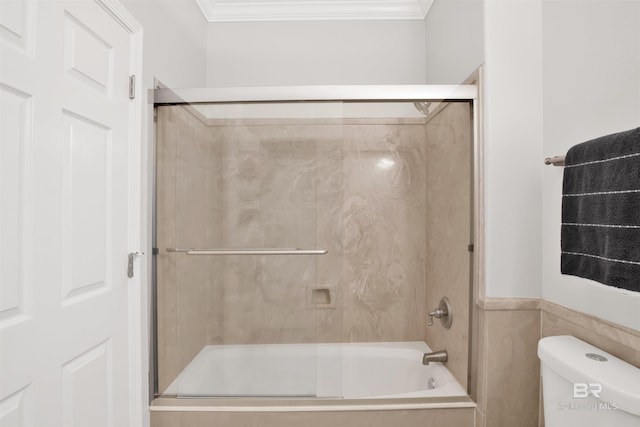 bathroom with combined bath / shower with glass door, toilet, and ornamental molding