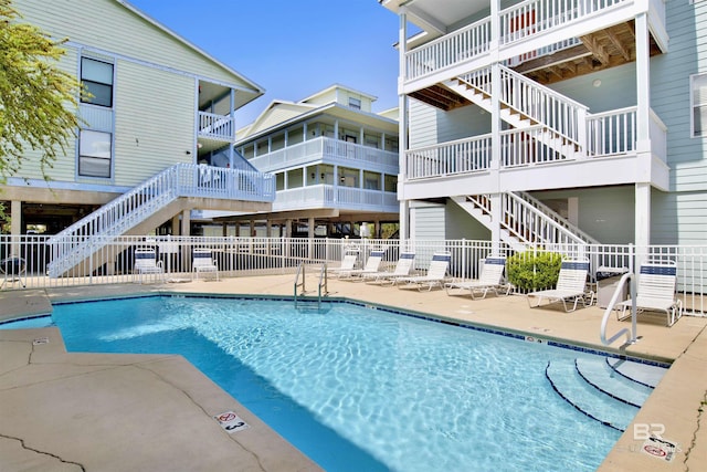 pool with a patio area, stairs, and fence