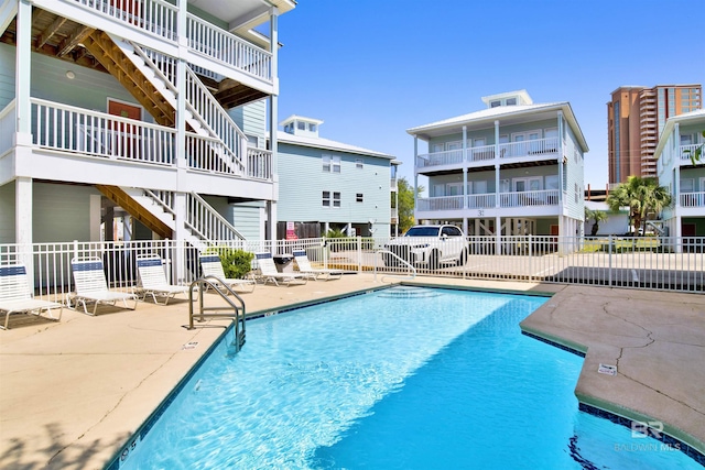 pool with stairs, fence, and a patio area