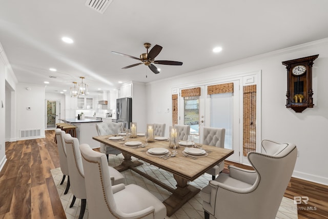 dining area featuring dark wood-type flooring, visible vents, and crown molding