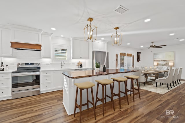 kitchen with stainless steel appliances, a kitchen island, decorative light fixtures, and white cabinets