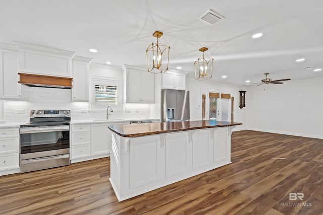 kitchen with decorative light fixtures, stainless steel appliances, visible vents, white cabinets, and a kitchen island