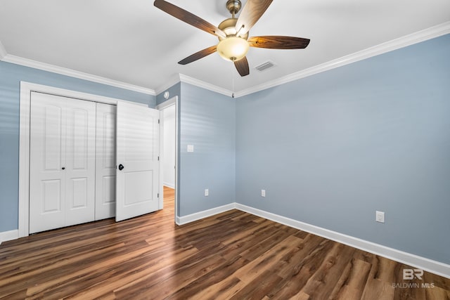 unfurnished bedroom with a closet, visible vents, dark wood-style flooring, and crown molding